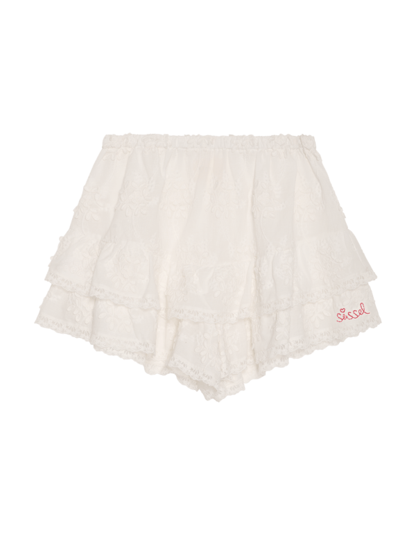 Delphine Shorts - Off White fra Sissel Edelbo. Delphine Shorts har en flagrende, feminin pasform og er lavet i en smuk resterende schiffli-bomuld. De har en elastisk linning for ekstra komfort. Shortsene er detaljeret med flæser langs hofterne og benåbningerne, inspireret af vintage-bloomers. Fine blondebånd pryder kanterne og tilføjer et yndefuldt touch. En broderet 'Sissel'-signatur er placeret foran som et delikat sidste touch.