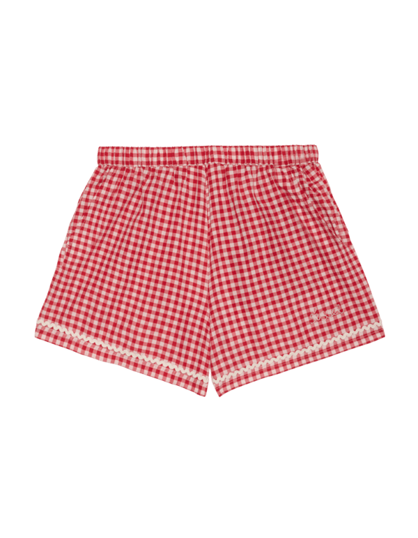 Bobbie Shorts - Red Checks fra Sissel Edelbo. Bobbie Shorts har en løs og afslappet pasform og er fremstillet af overskydende garnfarvet bomuld. De har en elastik i taljen, der bidrager til den behagelige pasform, samt lommer i sidesømmene og en baglomme. Shortsene er dekoreret med et sødt jordbærmotiv – udført i applikeret bomuld og broderi – på baglommen og afsluttet med et markant zigzag-bånd langs benåbninger og lommekanter.